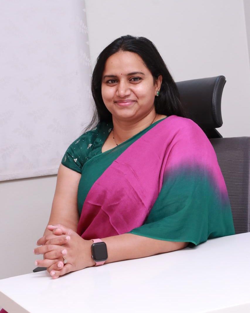 Dr. Palaparthi Lalitha Devi, seated at her desk, in a green and magenta saree